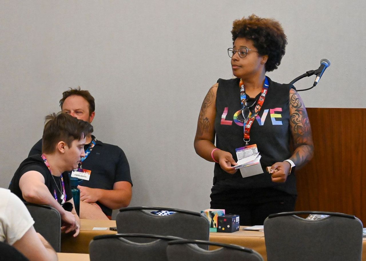 Woman wearing love tshirt presenting at Gen Con Trade Day