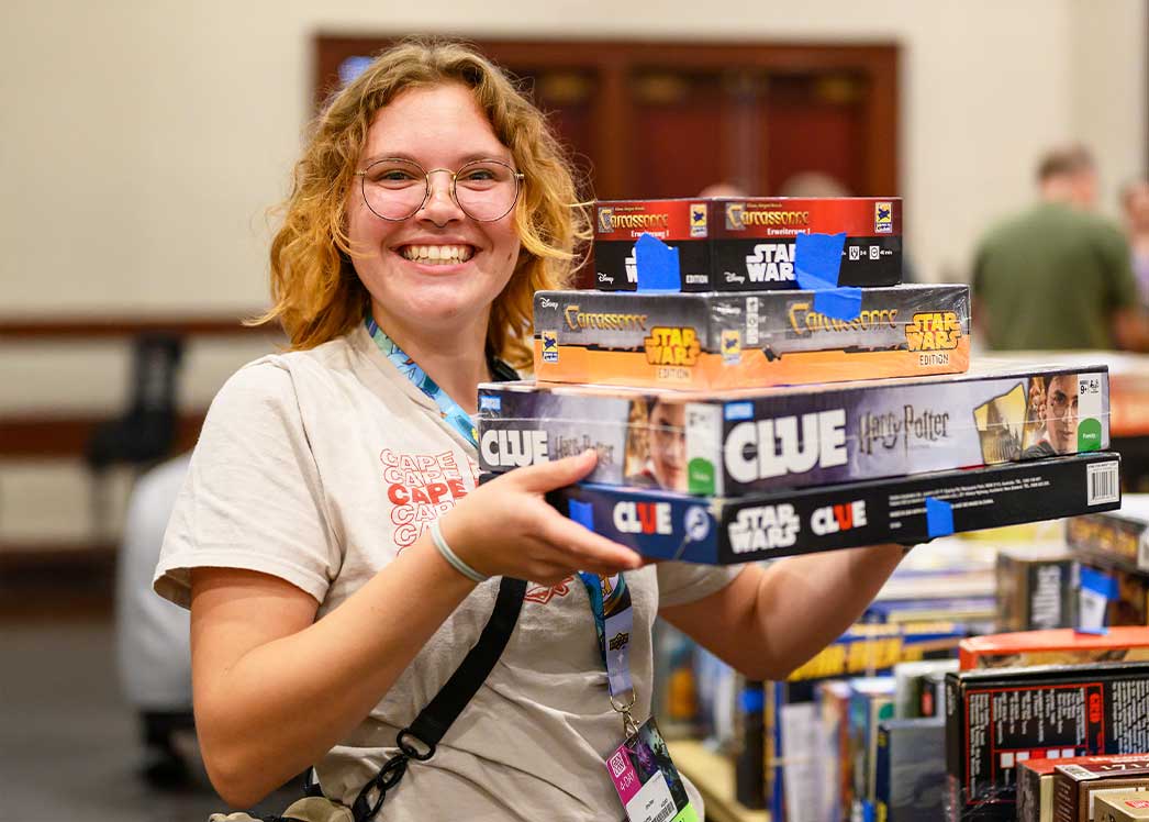 woman holding stack of board games
