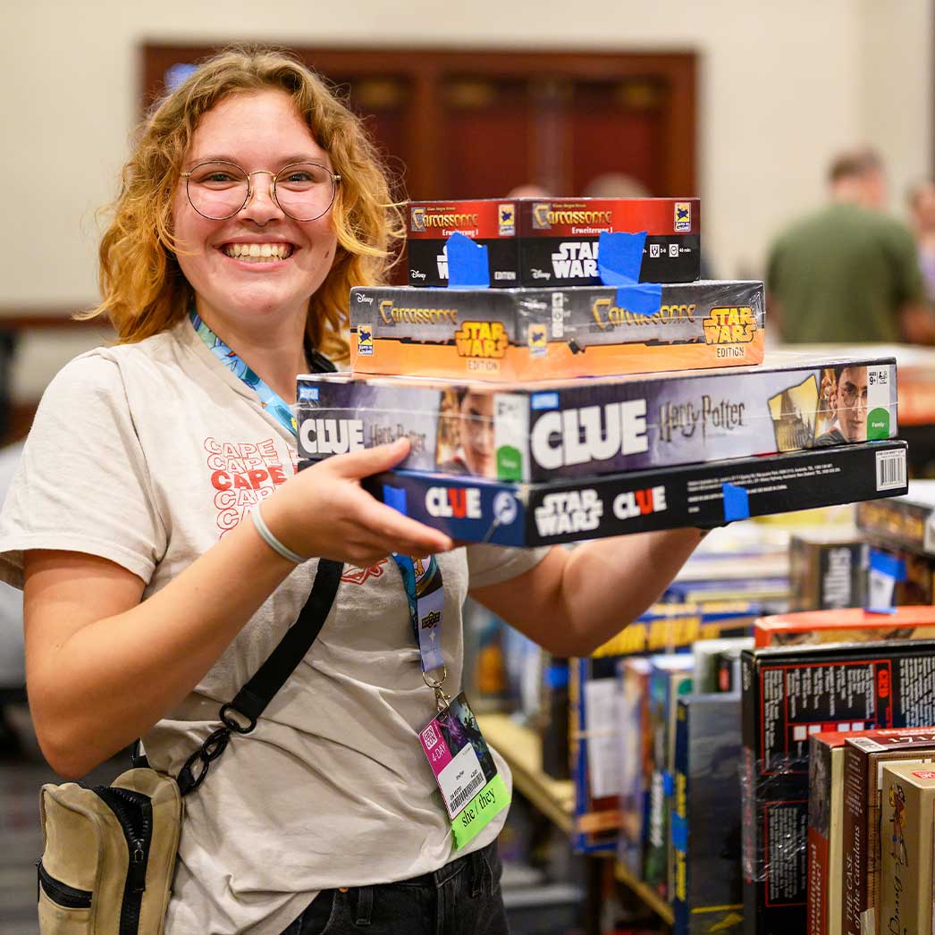 woman holding stack of board games
